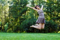 smiling beautiful happy girl jumping in a park in summer