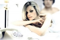 Žena v posteli kouká na telefon